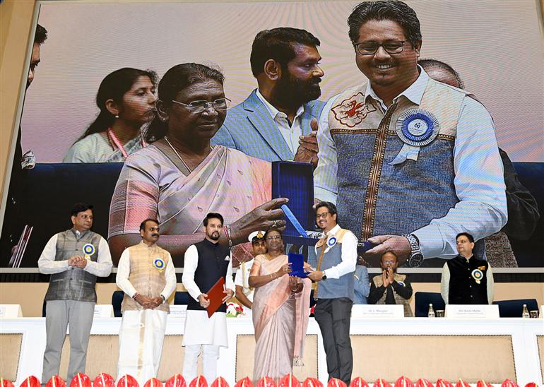 The President of India, Smt Droupadi Murmu confers Shri Monjul Baruah Director Best Assamese Film (Anur - Eyes on the Sunshine) at the 69th National Film Awards ceremony, in New Delhi on October 17, 2023. The Union Minister for Information & Broadcasting, Youth Affairs and Sports, Shri Anurag Singh Thakur and the Minister of State for Fisheries, Animal Husbandry & Dairying, Information and Broadcasting, Dr. L. Murugan are also present.