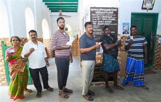 Voters displaying identity cards while standing in the queue to cast their votes at a polling booth during the 1st Phase of General Elections-2024 at Alamelu Mangai Thayarammal Montessori School, in Chennai on April 19, 2024.