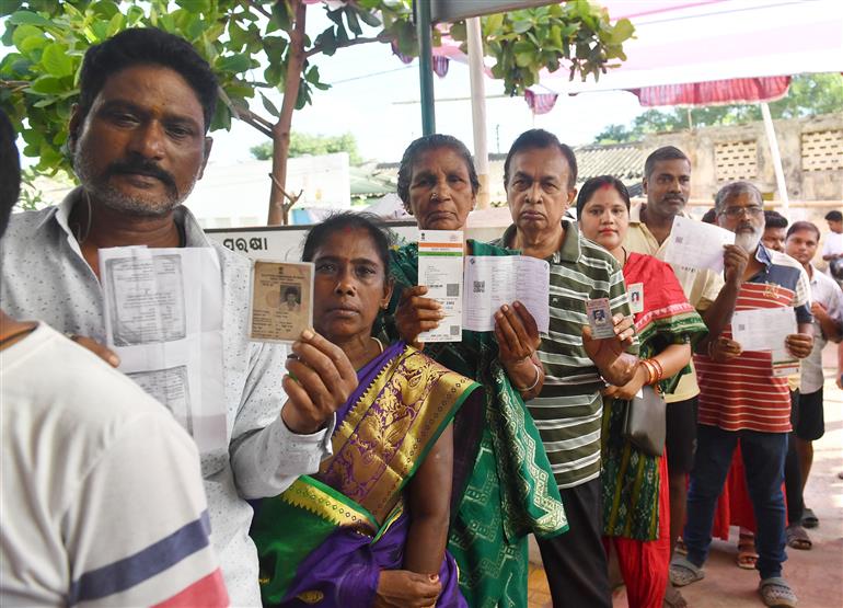 Voters displaying identity cards while standing in queue to cast their votes at a polling booth during the 6th Phase of General Elections-2024 at Govt Primary School NAC Colony in Bhubaneswar, Odisha on May 25, 2024.