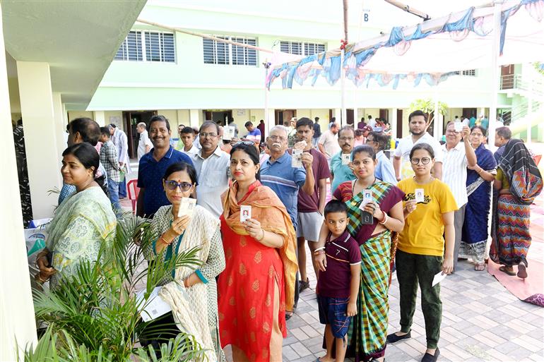 Voters displaying identity cards while standing in queue to cast their votes at a polling booth during the 6th Phase of General Elections-2024 at Govt. High School IRC Village, in Bhubaneswar, Odisha on May 25, 2024.