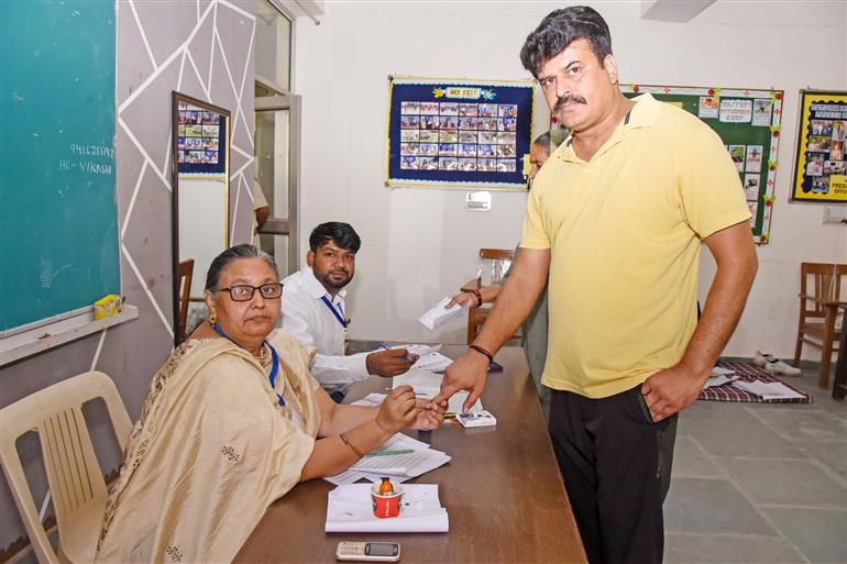 A polling official administering indelible ink to the voters after casting their votes at a polling booth during the Legislative Assembly Elections 2024 at G.V.M. Girls College in Sonipat, Haryana on October 05, 2024.