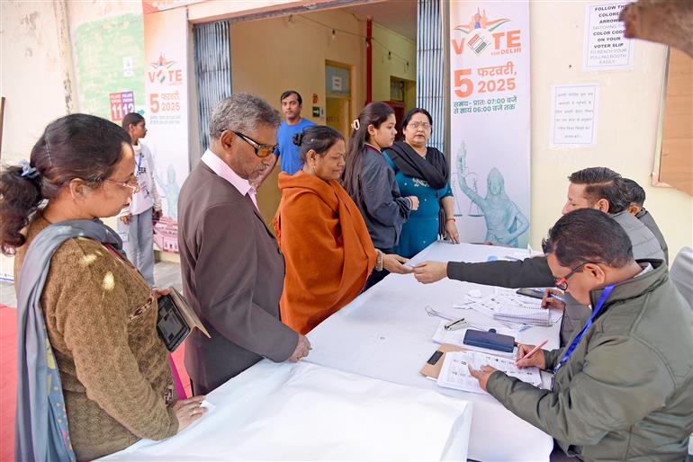 The Voters are being assisted by election officials at a polling booth during the Delhi Assembly Election 2025 at Gole Market, in New Delhi on February 05, 2025.