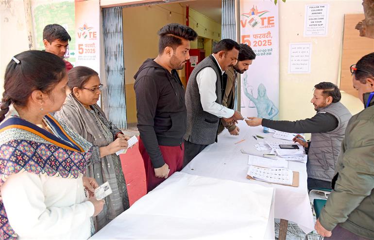 The Voters are being assisted by election officials at a polling booth during the Delhi Assembly Election 2025 at Gole Market, in New Delhi on February 05, 2025.