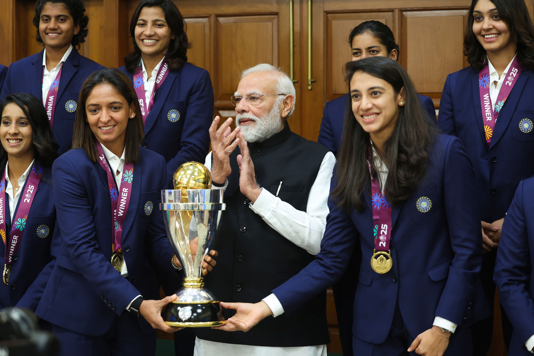 Harmanpreet Kaur with the Indian women's cricket team and 2025 Women's Cricket World Cup trophy