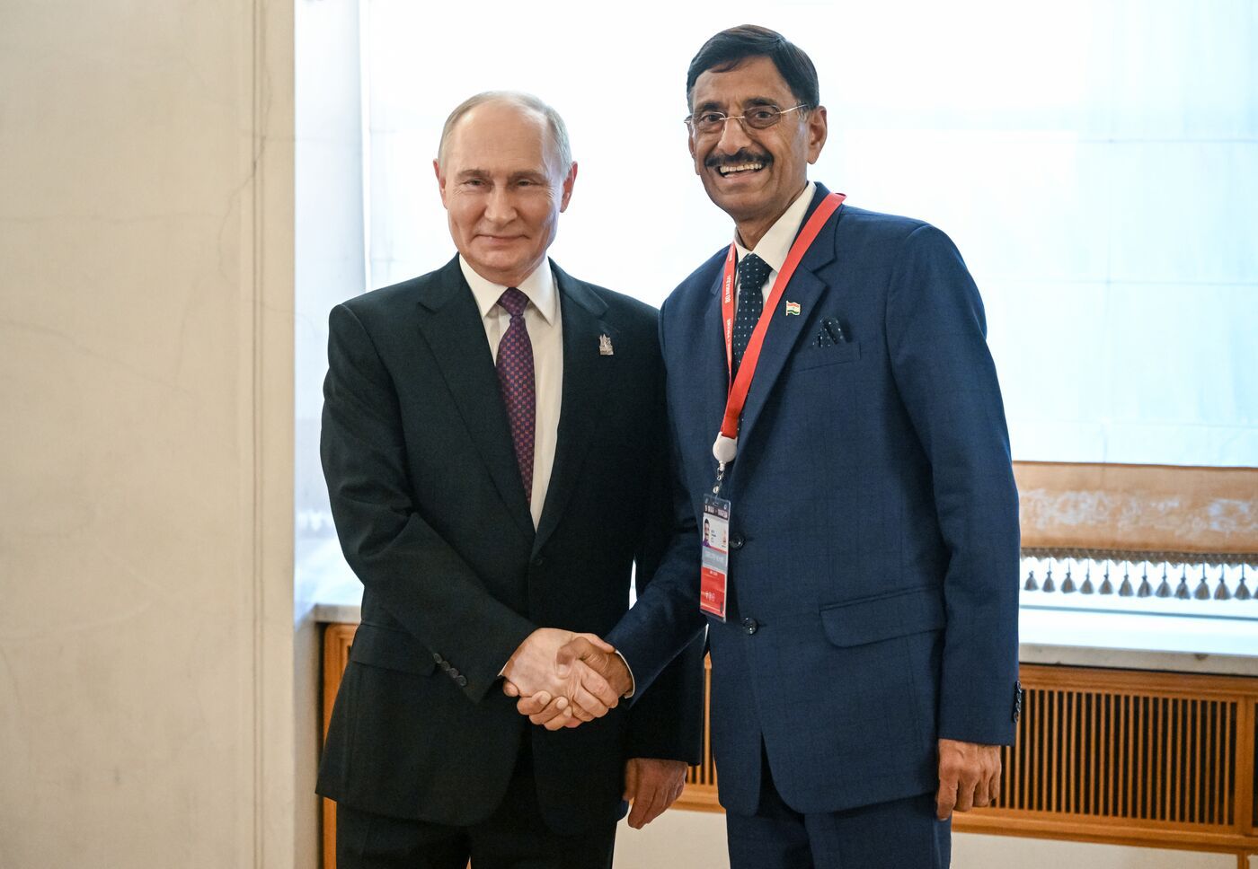 A person in suit shaking hands with another person in suitDescription automatically generated