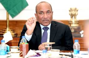 A person in a suit sitting at a tableDescription automatically generated