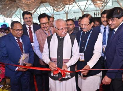 A group of people cutting a red ribbonDescription automatically generated