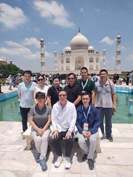 A group of people posing for a photo in front of a large buildingDescription automatically generated