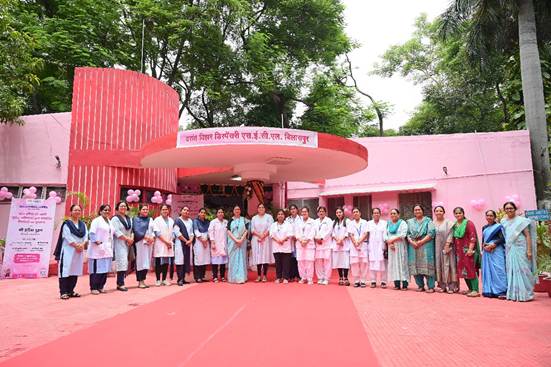A group of people standing in front of a pink buildingDescription automatically generated
