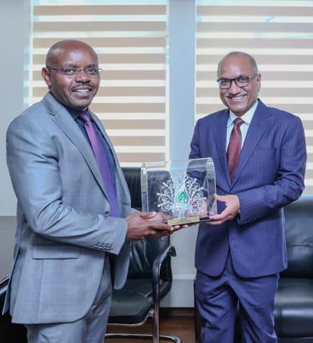 Two men in suits holding a glass caseDescription automatically generated