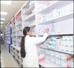A person in a white coat in a pharmacyDescription automatically generated