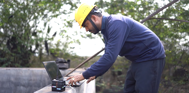 A person wearing a hard hat and holding a computerDescription automatically generated