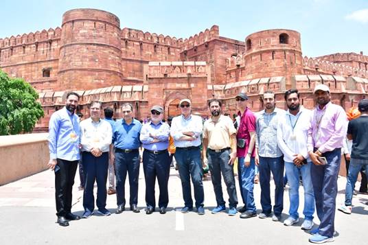 A group of men standing in front of a large brick buildingDescription automatically generated