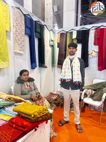 A person and person standing in front of a display of colorful fabricsAI-generated content may be incorrect.