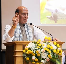 A person standing at a podium with a microphone and a microphoneDescription automatically generated