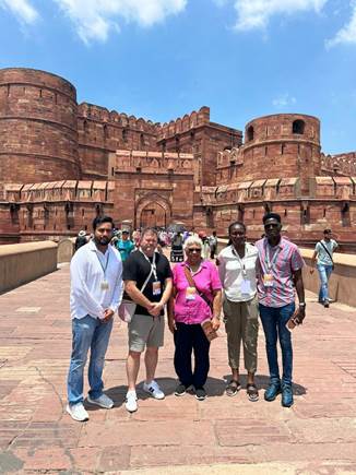 A group of people posing for a photo in front of a large brick castleDescription automatically generated