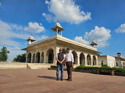 A couple of men standing in front of a buildingDescription automatically generated