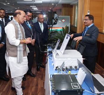 A group of men standing around a table with computersDescription automatically generated