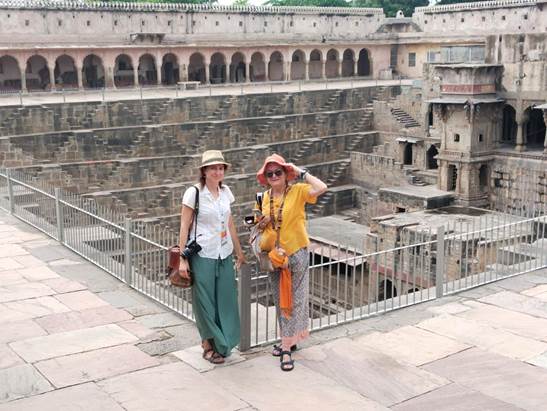 Two women standing in front of a metal fenceDescription automatically generated