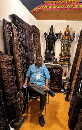 A person sitting in a chair in a room with many carved wood carvingsAI-generated content may be incorrect.